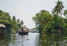 some houses are floating on the water near palm trees and other small buildings in the background