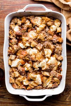 a casserole dish filled with meat and cheese on top of a wooden table