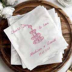 four napkins with pink ink on them sitting on a wooden plate next to flowers