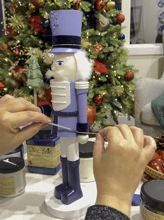 two people are decorating a nutcracker in front of a christmas tree