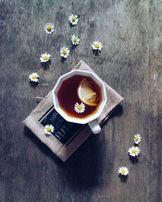 a cup of tea and some daisies on a table