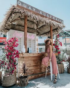 a woman in a straw hat is sitting on a bench at the quay australia stand