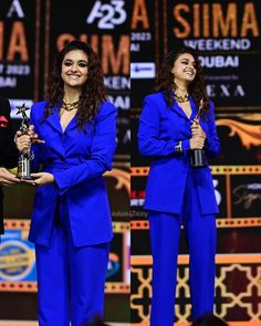 two women in blue suits holding trophies on stage