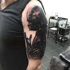 a man with a black and grey tattoo on his arm wearing a darth vader helmet