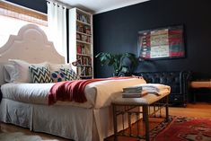 a bedroom with black walls, white bedding and a red rug on the floor