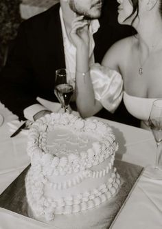 a man and woman sitting next to each other at a table with a cake on it