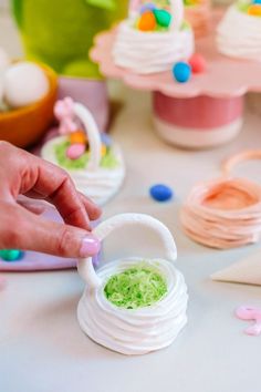 a person is decorating small cupcakes with icing and sprinkles