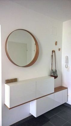 a white cabinet with a mirror and vase on the wall next to it in a room