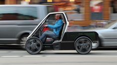 a man is driving an electric car down the street