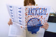 a woman is holding up a book with an article in front of her face and reading it