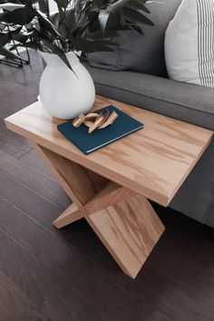 a wooden table with a white vase on top of it next to a gray couch