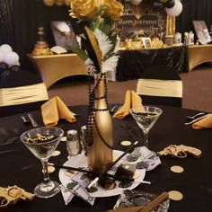 a black table topped with gold and white decorations next to wine glasses and champagne flutes