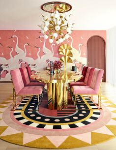 a pink and gold dining room with flamingos painted on the wall behind the table