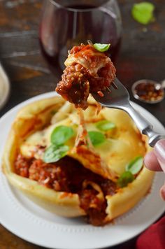 a person is holding a fork over a deep dish pizza on a white plate with sauce and basil