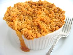 a close up of a cake in a cup on a plate with a fork next to it