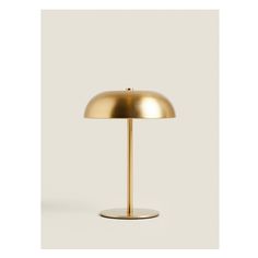 a gold lamp on a white background with the light turned off and it's base is