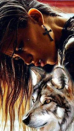 a woman is kissing a wolf with her eyes close to her face, while the wolf looks on