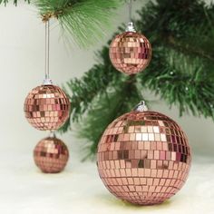 three shiny disco ball ornaments hanging from a christmas tree