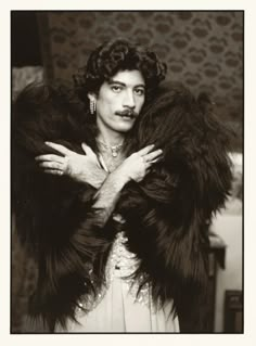 an old black and white photo of a woman in a fur coat with her hands on her chest