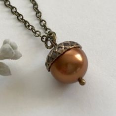 Perfect for fall or year round, here is a sweet copper acorn necklace consisting of one high quality, copper colored glass pearl which is topped with a solid brass acorn bead cap. This sweet fall necklace comes on a soldered brass chain with a solid brass clasp closure. Necklace comes in a variety of lengths, please select from the drop down menu. The acorn pearl measures: 12 mm in diameter. All materials are lead and nickel free. Handcrafted in the USA, this necklace is shipped in a Botanical B Victorian Acorn Necklace, Hollow Acorn Necklace, Acorns Necklace, Acorn Jewelry, Oak Leaf Necklace, Fall Necklace, Swarovski Pearl Necklace, Woodland Earrings, Acorn Pendant