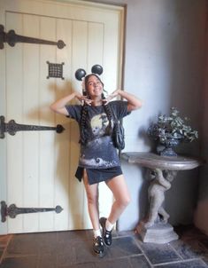 a woman standing in front of a door with her hands on her head while wearing mickey ears