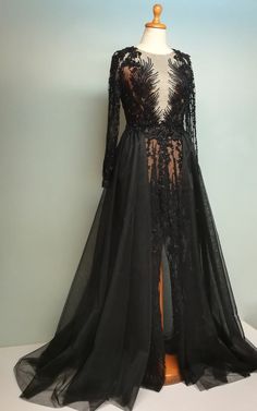 a black dress with long sleeves and sheer lace on the bottom, sitting on a mannequin