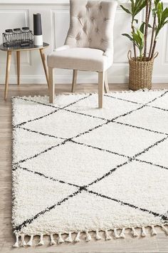 a white and black rug with tassels on the floor next to a chair