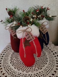 two red and blue christmas stocking vases on a doily with pine cones