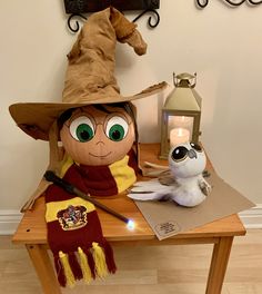 a stuffed animal is sitting on a table next to a harry potter hat and lamp