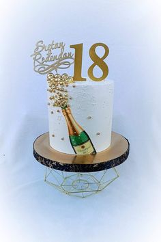 a white and gold birthday cake with a bottle of champagne