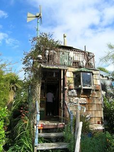 an old outhouse is surrounded by plants and trees