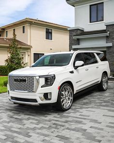 a white suv is parked in front of a house on a cobblestone driveway