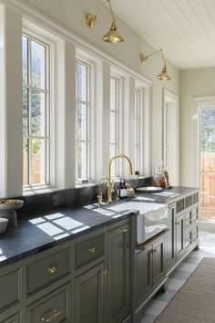 a large kitchen with two sinks and three windows