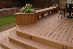 a wooden deck with planters on the top and stairs leading up to an outdoor dining area