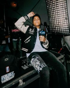 a young man sitting in front of a recording booth holding a microphone and looking up