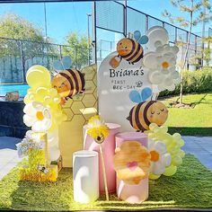 a display with balloons and honeybees on the grass in front of a fence