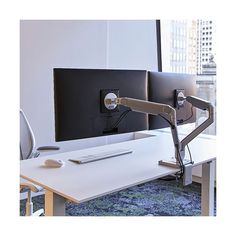 an office desk with a monitor and keyboard on it, in front of a window