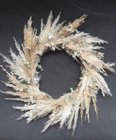 a wreath made out of dried grass and baby's breath flowers on a black background