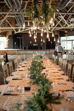 a long table is set up with place settings and greenery for an elegant wedding reception