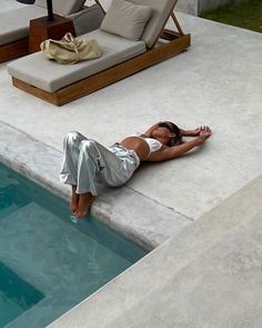 a woman laying on the edge of a swimming pool