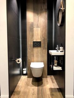 a modern bathroom with wood flooring and black walls, along with a white toilet