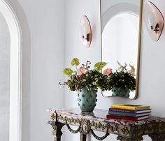 two vases filled with flowers sitting on top of a table next to a mirror