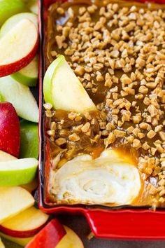 an apple dessert in a red dish with nuts and caramel on top, surrounded by sliced apples