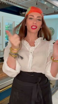 a woman in a white shirt and black skirt holding up two fingers with both hands