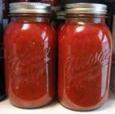 two jars filled with red sauce sitting on top of a counter