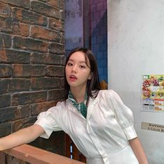 a woman leaning against a brick wall with her hand on the back of a wooden bench