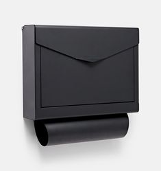 a black mailbox mounted to the side of a wall next to a roll of toilet paper