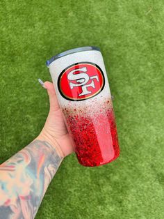 a hand holding a red and white cup with the san francisco giants on it