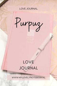 a pink notebook with the words love journal and a pen sitting on top of it