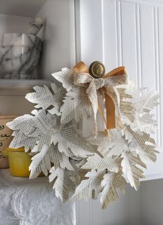 a wreath made out of old book pages is hanging on the front door with a ribbon